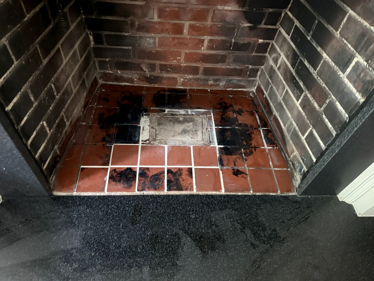 Original fireplace hearth with damaged tile before restoration